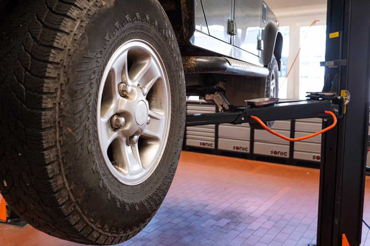 New car rubber tire on a suspended car in a repair shop. Close up, wide angle view, no people