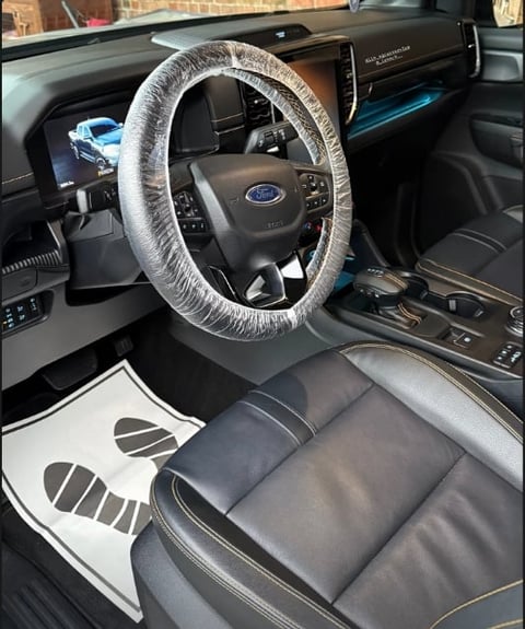 Ford vehicle interior with clear plastic steering wheel cover and black leather seats