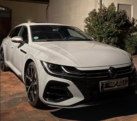 White Volkswagen Arteon parked in driveway with modern black and white exterior design
